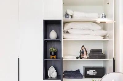 a room with a shelf with towels and a tv at Premium Apartment mit Strandzugang in Dubai in Dubai