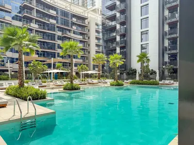 a swimming pool with palm trees and buildings at Silkhaus Chic Studio in Sobha Hartland at Kensington in Dubai