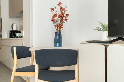 a table with two chairs and a vase with flowers at Silkhaus Chic Studio in Sobha Hartland at Kensington in Dubai