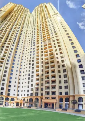 a large building with a green field in front of it at Luxury Modern Apt in JBR 2 MIN to BEACH in Dubai