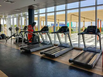a gym with several treadmills and elliptical machines at PVH - Golf Vita - 1BR with Golf Course View in Dubai