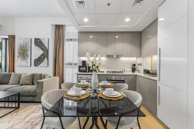 a kitchen and living room with a glass table and chairs at Sleek Cozy Apartments in Meydan in Dubai