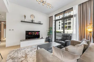 a living room with a couch and a tv at Sleek Cozy Apartments in Meydan in Dubai