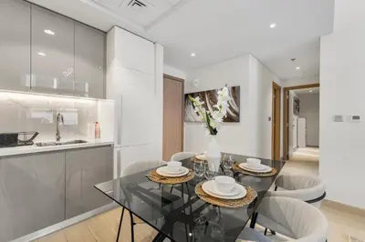 a kitchen and dining room with a glass table and chairs at Sleek Cozy Apartments in Meydan in Dubai
