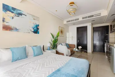 a bedroom with a large bed and a kitchen at The Minimalist JLT Studio in Dubai