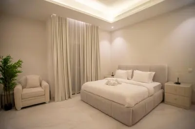 a white bedroom with a bed and a chair at Luxury 5 Bedroom Villa Nad Al Sheba in Dubai