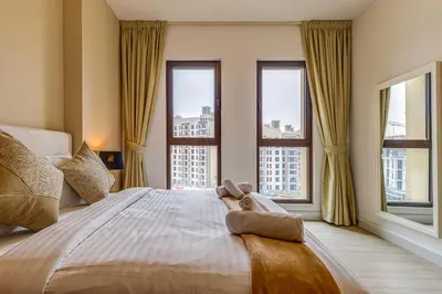 a bedroom with a large bed with two windows at Elegant 2 Bedroom Apartment - Jadeel 2, Madinat Jumeirah - Allsopp & Allsopp in Dubai