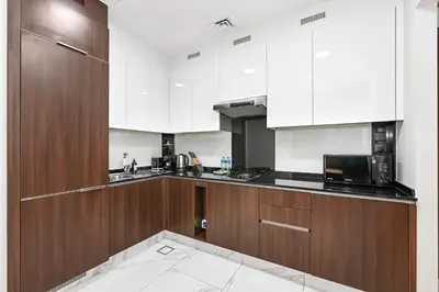 a kitchen with wooden cabinets and a microwave at Unwind in a Stylish Studio with Pool, Sauna, and Stunning City Views in Dubai