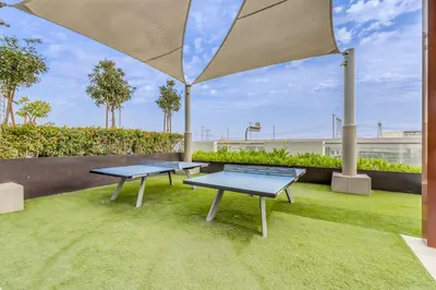 two ping pong tables on a lawn with an umbrella at 1BR Royal Bedroom with Pool & Gym Free in Dubai