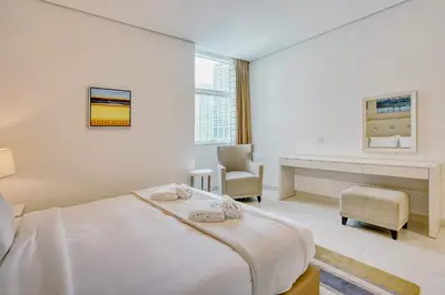 a white bedroom with a bed and a desk at PVH - Refined 1BR in Business Bay - Cour Jardin in Dubai