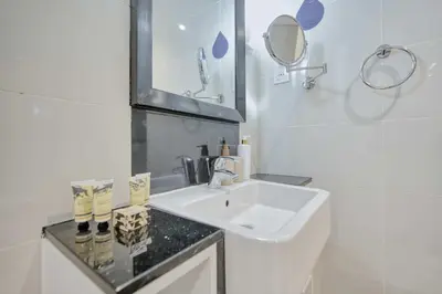 a white bathroom with a sink and a mirror at PVH - Refined 1BR in Business Bay - Cour Jardin in Dubai