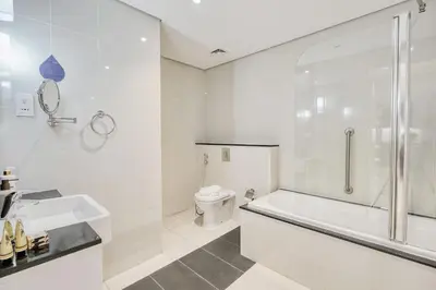 a white bathroom with a tub and a toilet at PVH - Refined 1BR in Business Bay - Cour Jardin in Dubai