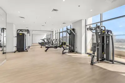 a gym with cardio equipment in a building with windows at Elite Apartments in Meydan in Dubai