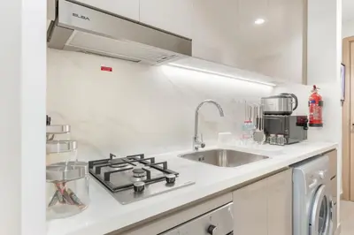 a white kitchen with a sink and a stove at Elite Apartments in Meydan in Dubai