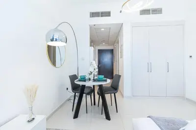 a white dining room with a table and chairs at PVH - Serene Studio with Skyline View - Carson B in Dubai