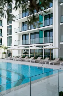 a swimming pool with chairs and umbrellas in front of a building at Newly Furnished Studio Haven in Binghatti Azure in Dubai
