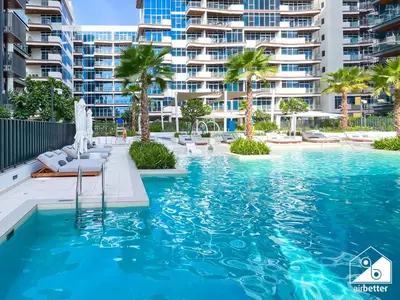 a swimming pool with palm trees and a large building at Comfort Studio in Meydan With Gym, Pool & Parking in Dubai