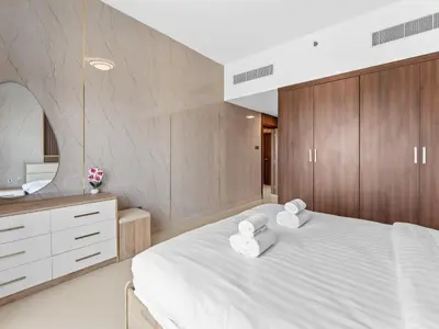 a bedroom with a large white bed with wooden cabinets at BLVD - Scenic View Stay with Pool and Gym Access in Dubai