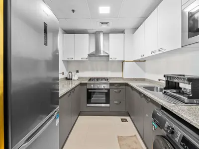 a kitchen with white cabinets and a stainless steel refrigerator at BLVD - Scenic View Stay with Pool and Gym Access in Dubai