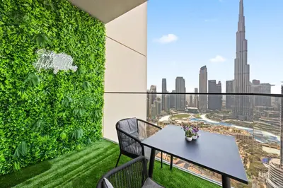 a balcony with a table and a green wall at 4BR Burj & Fountain View Luxe in Dubai
