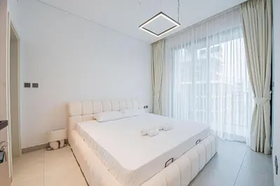 a white bed in a room with a large window at Chic 2BR Flat in Park Lane Dubai in Dubai