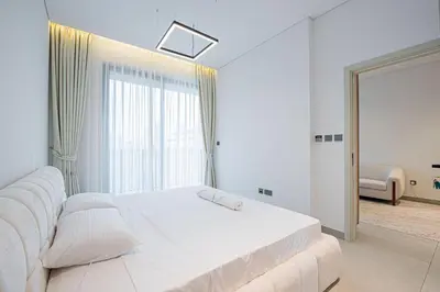 a white bedroom with a bed and a window at Chic 2BR Flat in Park Lane Dubai in Dubai