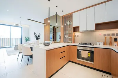 a kitchen with wooden cabinets and a dining room at Chic 2BR Flat in Park Lane Dubai in Dubai