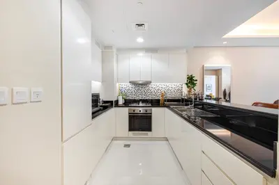 a kitchen with white cabinets and black appliances at Fabulous 2 BR - Paramount Midtown in Dubai