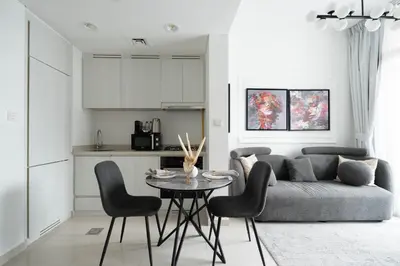 a living room with a couch and a table and chairs at KeyRock - Modern 1BR in Zada with Pool & View in Dubai