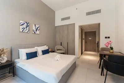 a hotel room with a bed and a desk and a room at HAVN - Brand New Studio in Oxford Boulevard, JVC in Dubai
