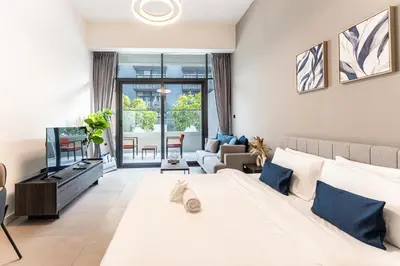 a bedroom with a large bed and a living room at HAVN - Brand New Studio in Oxford Boulevard, JVC in Dubai