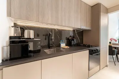 a kitchen with white cabinets and a counter top at HAVN - Brand New Studio in Oxford Boulevard, JVC in Dubai