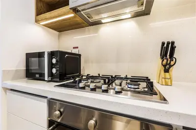 a kitchen with a stove and a microwave at Luxury Skyline View 1BR with Pool, Gym, Parking, Concierge & Near Metro in Dubai