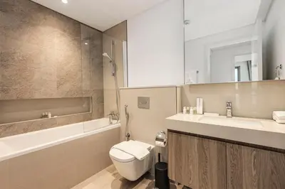 a bathroom with a toilet and a sink and a tub at Luxury Skyline View 1BR with Pool, Gym, Parking, Concierge & Near Metro in Dubai