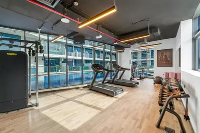 a gym with treadmills and a swimming pool at Tranquil 1BR Prime Arjan in Dubai