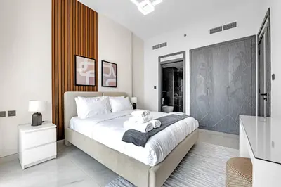 a white bedroom with a large bed with towels on it at Tranquil 1BR Prime Arjan in Dubai