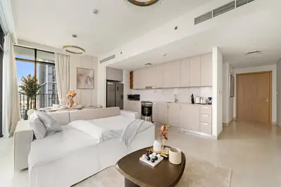 a white living room with a white couch and a kitchen at Prime 2BR Retreat, Creek Harbour Views & Comfort Near Restaurants in Dubai