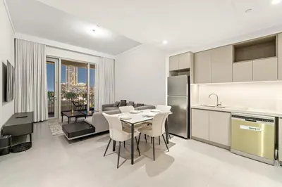 a kitchen and living room with a table and chairs at Luxury 2BR Dubai Creek Harbour with Pool, Gym, Parking & Balcony Views in Dubai