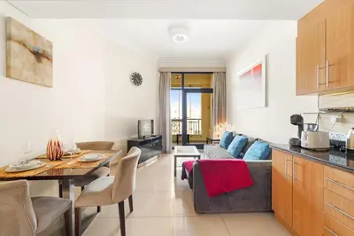 a kitchen and living room with a couch and a table at Dubai 1BR Balcony Views Near Miracle Garden in Dubai