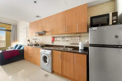 a kitchen with a refrigerator and a dishwasher at Dubai 1BR Balcony Views Near Miracle Garden in Dubai