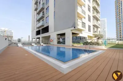 a building with a swimming pool in front of a building at Vogue JVC Jeewar Tower near Circle Mall, One Bedroom Apartment with Balcony and City View, Access to all Amenities in Dubai