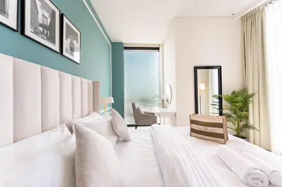 a bedroom with a large white bed with a blue wall at Luxury 1BR Sea View Apt Address JBR Dubai in Dubai