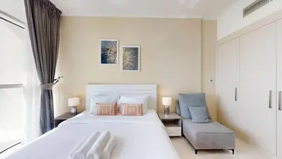 a bedroom with a large white bed and a chair at Carson A - High Rise Cosy Studio with City Views in Dubai