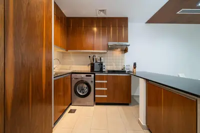 a kitchen with wooden cabinets and a washing machine at Modern Studio in the Heart of Sports City in Dubai