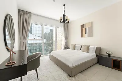 a white bedroom with a bed and a large window at Sea View 2BR Apartment With Private Beach in Dubai