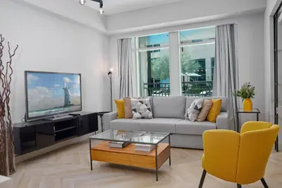 a living room with a couch and a tv at Vista Downtown Poolside 1BR Walk to Burj Khalifa in Dubai