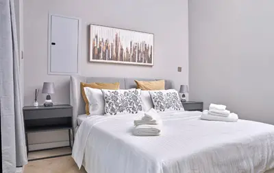 a white bedroom with a large white bed with pillows at Vista Downtown Poolside 1BR Walk to Burj Khalifa in Dubai