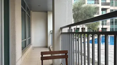 a bench sitting on a balcony with a view of a pool at Vista Downtown Poolside 1BR Walk to Burj Khalifa in Dubai