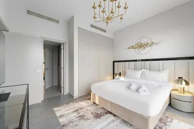 a bedroom with a large white bed and a chandelier at FIRST CLASS Villa Private Pool & Garden Bliss in Dubai