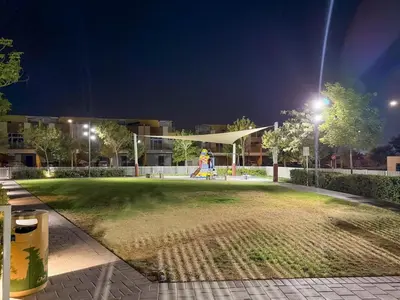 a park at night with a person walking in the grass at FIRST CLASS VILLA Spacious for Family Getaways in Dubai
